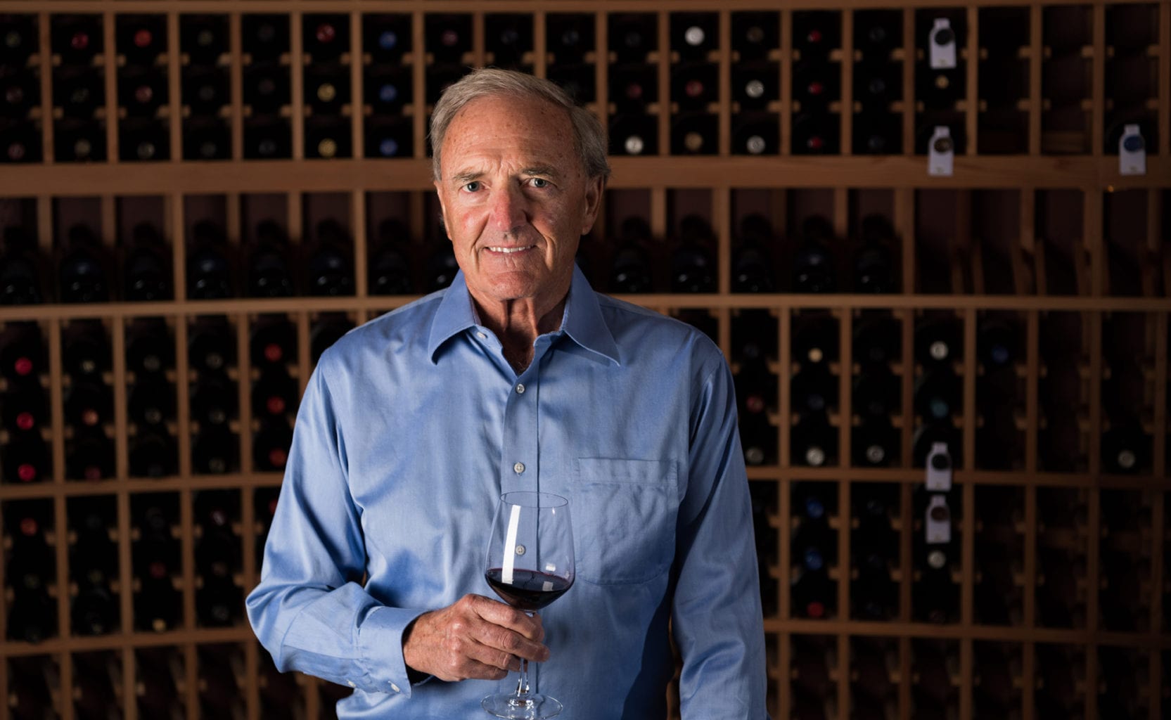 Ron Noble with a glass of Pinot Noir in the wine cellar